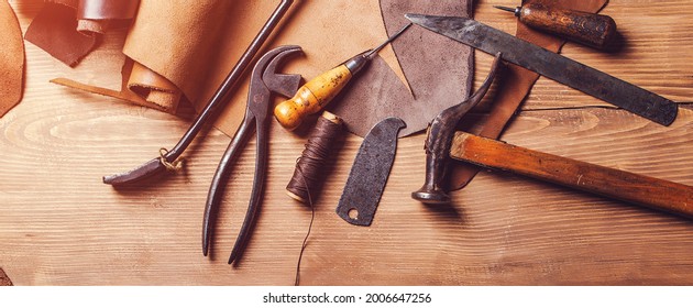 Leather craft tools on old wooden table. Leather craft workshop. Shoemaker's work desk. Tools and leather at cobbler workplace. Working tools on leather craftman's work desk. - Powered by Shutterstock