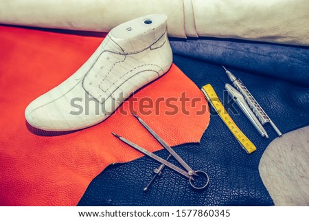 Leather craft tools on wooden background. Workplace for shoemaker. Cobbler workplace with tools, leather and shoes last. Shoemaker workplace with tools. Selective focus and small depth of field.