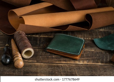 Leather craft or leather work. On work table of leathersmith there are pieces of leather, tool, waxed thread and leather wallet. - Shutterstock ID 1777678649