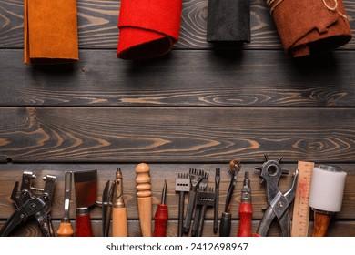 Leather and leather craft work tools instruments on the old wooden workbench flat lay background with copy space. Top view.