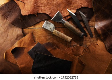 Leather craft or leather working. Leather cutting tools and selected pieces of tanned leather on craftman's work desk . Top view.