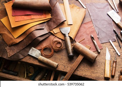 Leather craft or leather working. Selected pieces of beautifully colored or tanned leather on leather craftman's work desk . 