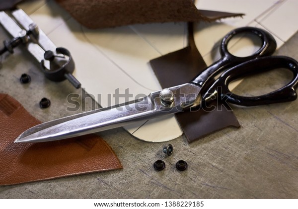 Leather crafting DIY tools and templates\
on workbench. Fittings and leather pieces with craft instruments\
for leather items\
manufacturing.