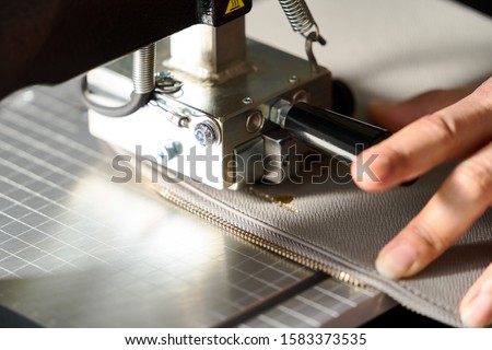 Leather crafting with leather engraving machine. Working process of making leather wallet in the leather workshop, close-up. 