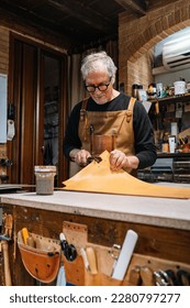 leather craftsman who dabs the edges of a piece of leather with a waterproof varnish, copy space