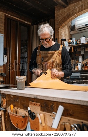 leather craftsman who dabs the edges of a piece of leather with a waterproof varnish, copy space Foto d'archivio © 