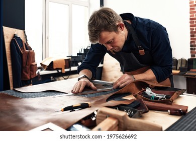 leather craftsmen working making measupenets in patterns at table in workshop studio - Powered by Shutterstock