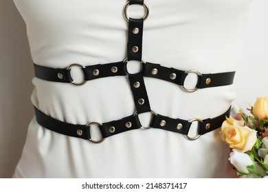 Leather detail of clothing close-up. Stylish belts on clothes. Black leather harness on white shirt
