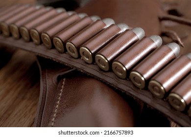 Leather gun belt with ammnunitions and revolver in holster on wooden table