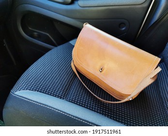 A leather handbag that is obviously lying on a passenger seat.