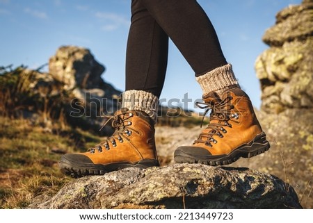 Leather hiking boot. Trekking in mountains. Female legs walking on rock