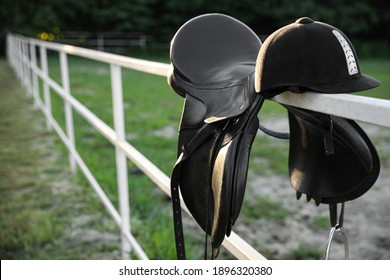 Leather horse saddle and helmet on wooden fence outdoors - Powered by Shutterstock