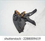 a leather jacket with fur collar abanoned on the snow, outdoor winter scene