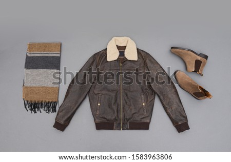 leather jacket with fur collar with and brown boots ,striped scarf isolated on gray background