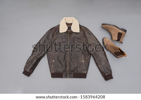 leather jacket with fur collar with and brown boots isolated on gray background

