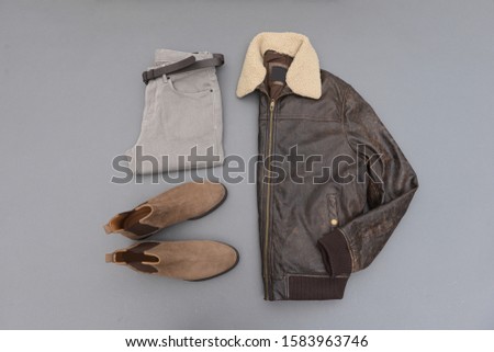 leather jacket with fur collar with khaki pants and brown boots isolated on gray background
