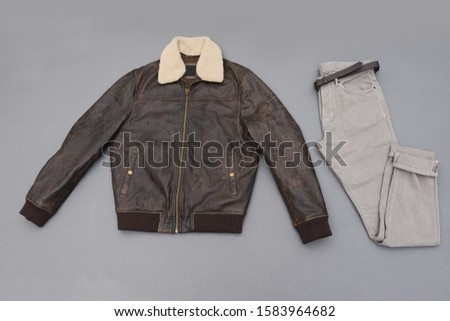 leather jacket with fur collar with khaki pants and brown boots isolated on gray background
