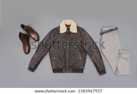 leather jacket with fur collar with khaki pants and brown boots isolated on gray background