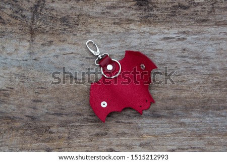 Leather keychain in Bat shape and old key in wooden door. - image