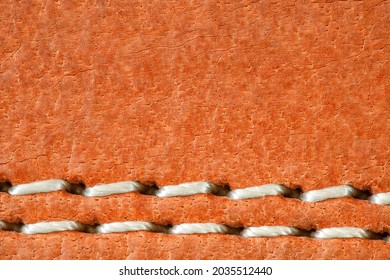 Leather is natural orange, seam is made of white threads, close-up macro view