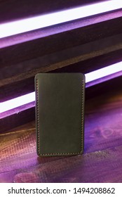 Leather Phone Case On A Wooden Background In Neon Light.