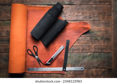 Leather pieces and leather craft work tools on the old wooden workbench background. - Powered by Shutterstock