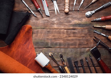 Leather pieces and leather craft work tools on the old wooden workbench background. - Powered by Shutterstock