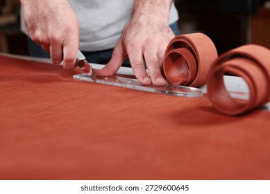 Leather processing master cuts leather in workshop. Manufacture of straps made of genuine leather or suede. Workflow in workshop. Handmade work.