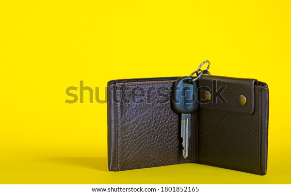 Leather purse\
with car key on yellow\
background
