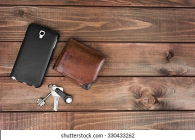 Leather Purse, Phone Pouch And Keys On A Wooden Table Background. Required Items For The Man At The Exit Of The House That Can Not Be Forgotten.