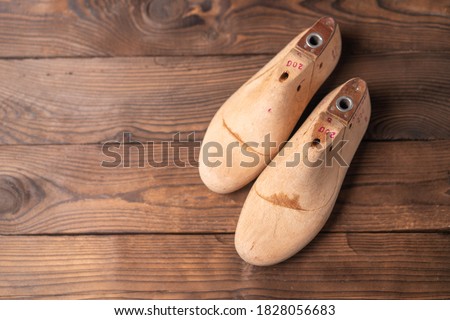 Leather samples for shoes and wooden shoe last on blue wooden table. Designer furniture clothes. Shoe maker workspace.