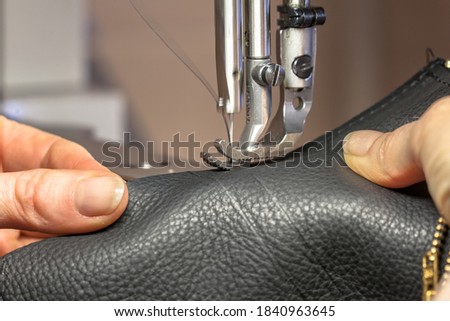Leather Sewing machine in action in workshop operated with hands working on garment