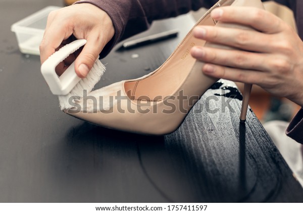 Leather shoes care concept.\
Shoe cleaning and polishing. Close up picture of woman hands\
cleaning shoes