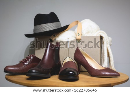 Leather shoes and a hat. Men’s and women’s accessories with brown shoes, classic hat on wooden table over white background. Vintage clothing. Retro clothing of the first half of the twentieth century.