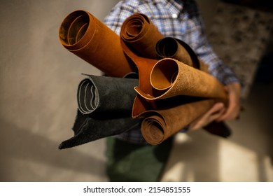 Leather shop. Sale of skin in rolls. Leather workshop. The master tanner holds rolls of leather in his hands. Brown and black genuine leather - Powered by Shutterstock