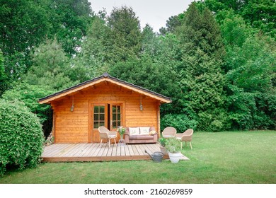 Leather sofa on a terrace outside next to a wooden house. Wooden garden house with outdoor seating. Relaxation in the garden. wooden hut. Big garden in Germany