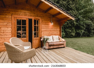 Leather sofa on a terrace outside next to a wooden house. Wooden garden house with outdoor seating. Relaxation in the garden. wooden hut