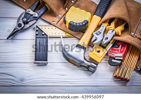 Leather tool belt with construction tooling on wooden board maintenance concept.