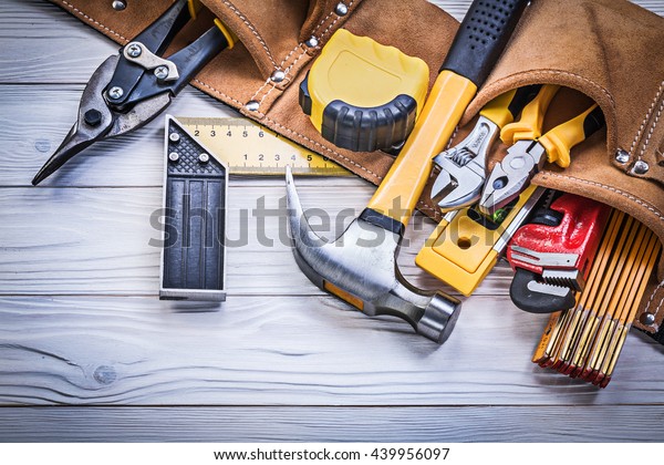 Leather tool belt with construction tooling on\
wooden board maintenance\
concept.
