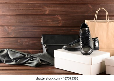 Leather upper metallic trendy womens shoes, scarf and black leather bag on brown wooden background. Shopping purchases