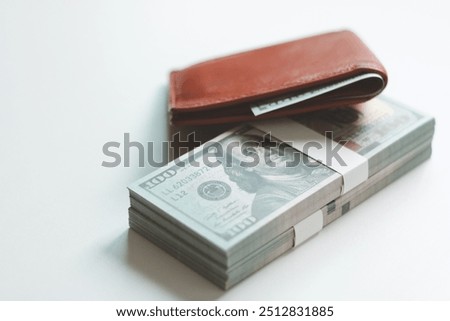 Leather wallet with American dollar banknotes on white background. One hundred dollar bills under orange leather wallet. Men's wallet money in cash. US currency, Financial, Accounting, Banking, Saving