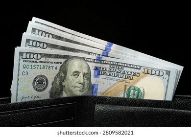 Leather wallet filled with a stack of new hundred-dollar bills. Cash, finance, savings, wealth. New hundred dollar bills in a leather wallet. New 100 dollar bills
