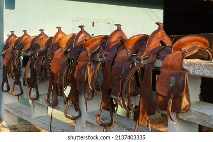 Leather Western Trail Saddles With Saddle Bags And Horns Lined Up On White Fence In Rural Cuba Saddle Bags Marked With Letters Horizontal Format Shot Before Horse Back Riding Adventure In Rural Cuba