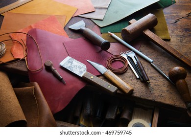 Leathersmith's work desk . Pieces of red, orange, yellow, green, tan and brown hide and leather working tools on a work table.