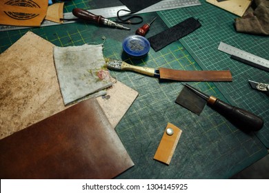 Leatherworking tools. Riveter, awl, ruler, pliers, tassels, pencil, leather pieces, rivets and fasteners are on the table. Close up photo. - Powered by Shutterstock