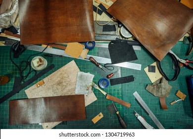 Leatherworking tools. Riveter, awl, ruler, pliers, tassels, pencil, leather pieces, rivets and fasteners are on the table. Close up photo. - Powered by Shutterstock