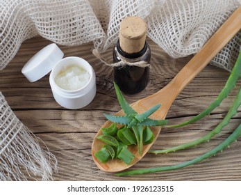 Leaves with aloe vera juice in a wooden spoon, syrup in a bottle, gel in a jar on a  wooden background, top view. Medicinal plant of aloe for use in medicine, homeopathy and cosmetology