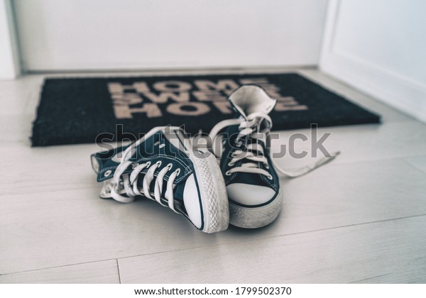 Leaving shoes on floor, at front door entrance\
outside home. Men removing their sneakers without placing them\
away. Tidy house cleaning\
concept.