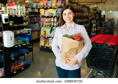 Leaving The Supermarket. Female Customer Carrying A Brown Bag With Fresh Vegetables And Food At The Grocery Store