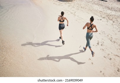 Leaving their mark on the track. High angle shot of two unrecognizable athletic young women out for a run on the beach. - Powered by Shutterstock